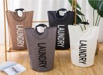 Four portable laundry baskets in brown, grey, black, and cream, with a handle and "LAUNDRY" printed on each.