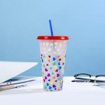A drink bottle with a red lid and straw, featuring a clear body decorated with colourful heart patterns.