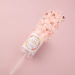 A clear container filled with pink and peach confetti, featuring a label and a straw.