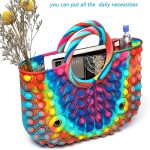 A colourful, multi-hued tote bag featuring raised bubble designs, with handles and contents including books and a drink bottle.