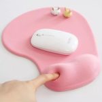 A pink office mousepad with a mouse on it and two small decorative animal figures.