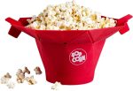 A red popcorn bucket filled with popcorn, featuring a logo and some spilled popcorn kernels around it.