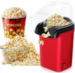 A red hot air popcorn maker with popcorn spilling out, accompanied by a bowl and a striped popcorn container.