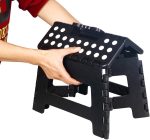 A black 11-inch folding step stool with a handle and holes for grip, being held by a hand.