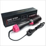 A one-step hair dryer and hot air brush in black and pink, with a round bristle head and a power cord.