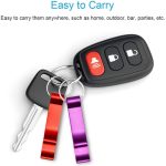 A drink bottle opener on a keyring, featuring purple and red attachments, accompanied by a car key with a logo.