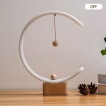 A white magnetic suspension balance lamp with a wooden base and a suspended wooden ball inside a circular design.