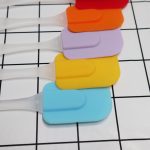 A set of cream spatulas in red, orange, purple, yellow, and blue, with transparent handles, arranged in a row.