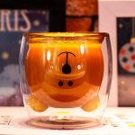 A cute bear-shaped glass tumbler in transparent and amber hues, featuring a playful bear design.