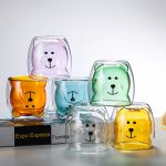 A set of cute bear-shaped glass tumblers in orange, green, purple, and clear glass, featuring playful bear faces.