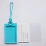 A blue silicone luggage tag with a clear insert for information and a protective cover.