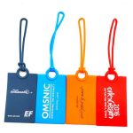 A set of four silicone luggage tags in blue, orange, red, and navy, featuring different logos and branding.