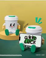 A coffee cup-shaped lamp Bluetooth speaker in white with green accents, featuring a character design and a mobile phone.
