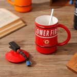 A red mug shaped like a fire extinguisher with a black lid and a straw, featuring a logo.