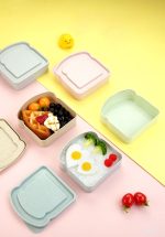 A set of colourful wheat straw bread boxes in pastel pink, blue, and green, featuring various food items inside.