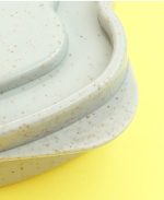 A wheat straw bread box in a soft grey-green colour with a speckled texture. It features a smooth, curved design.