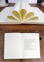 A notebook with eco-friendly coffee grounds pages, featuring a brown cover and lined pages, open to show inside.