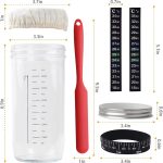 A 32 oz. clear Mason fermenter jar with a red silicone spatula, lid, fabric cover, and measurement tools, featuring a logo.