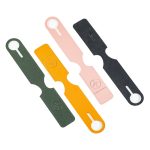 Four leather luggage tags in green, orange, pink, and black, each featuring a circular cutout and a logo.