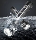 A sleek black flashlight lies above water, showcasing its durable design and LED light. It features a logo on the body.