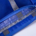 A blue lunch cooler tote with a silver insulated lining and grey accents, partially zipped open.