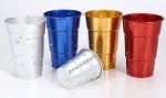 A set of rolled edge aluminium cups in silver, blue, gold, red, and one tilted, featuring water droplets.