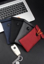 A collection of Faraday Bags in navy, black, grey, and red, beside a car key, set on a laptop background.