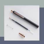 A black and rose gold metal push-up pen with a removable nib and a spring.