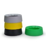 A stack of four coasters in grey, yellow, black, and green, with one green coaster positioned separately.