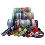 A variety of vibrant 1'' RPET elastic wristbands in different colours and patterns, with several featuring logos.