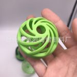 A green silicone ball with a spiral design, held in a hand, featuring an open structure.