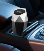 A geometric black and white car trash can sits in a car's cup holder, featuring a 'PUSH' top and a sleek design.