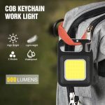 A black COB keychain work light with a yellow panel attaches to a grey bag, featuring a logo and a hook.