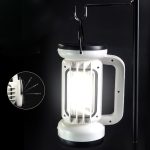 A white rechargeable COB lantern with a black top and handle, suspended from a hook.