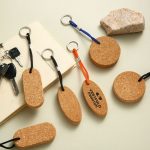 A cork floating key tag in various shapes, featuring black, orange, and blue attachments, alongside a few key sets and a rock.