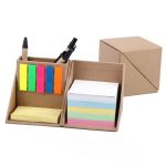 A desk organiser with coloured sticky notes, highlighters, and pens in a brown cardboard holder.