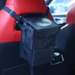 A foldable black car trash can is attached to a red car seat, featuring a secure strap and mesh pocket.