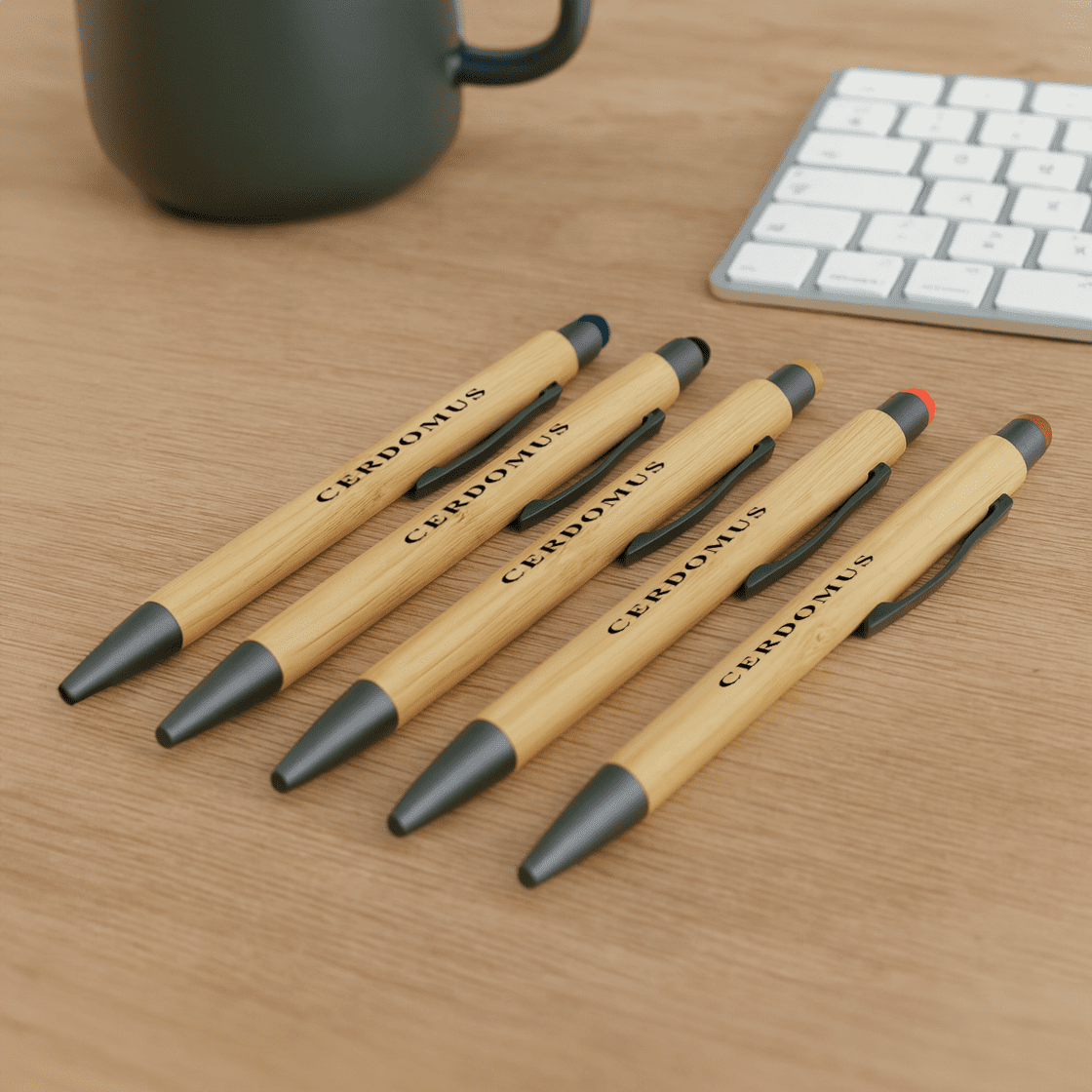 A set of bamboo pens in natural wood and black, featuring a logo, displayed on a wooden surface. Manopoli Bamboo Pen - Image 1