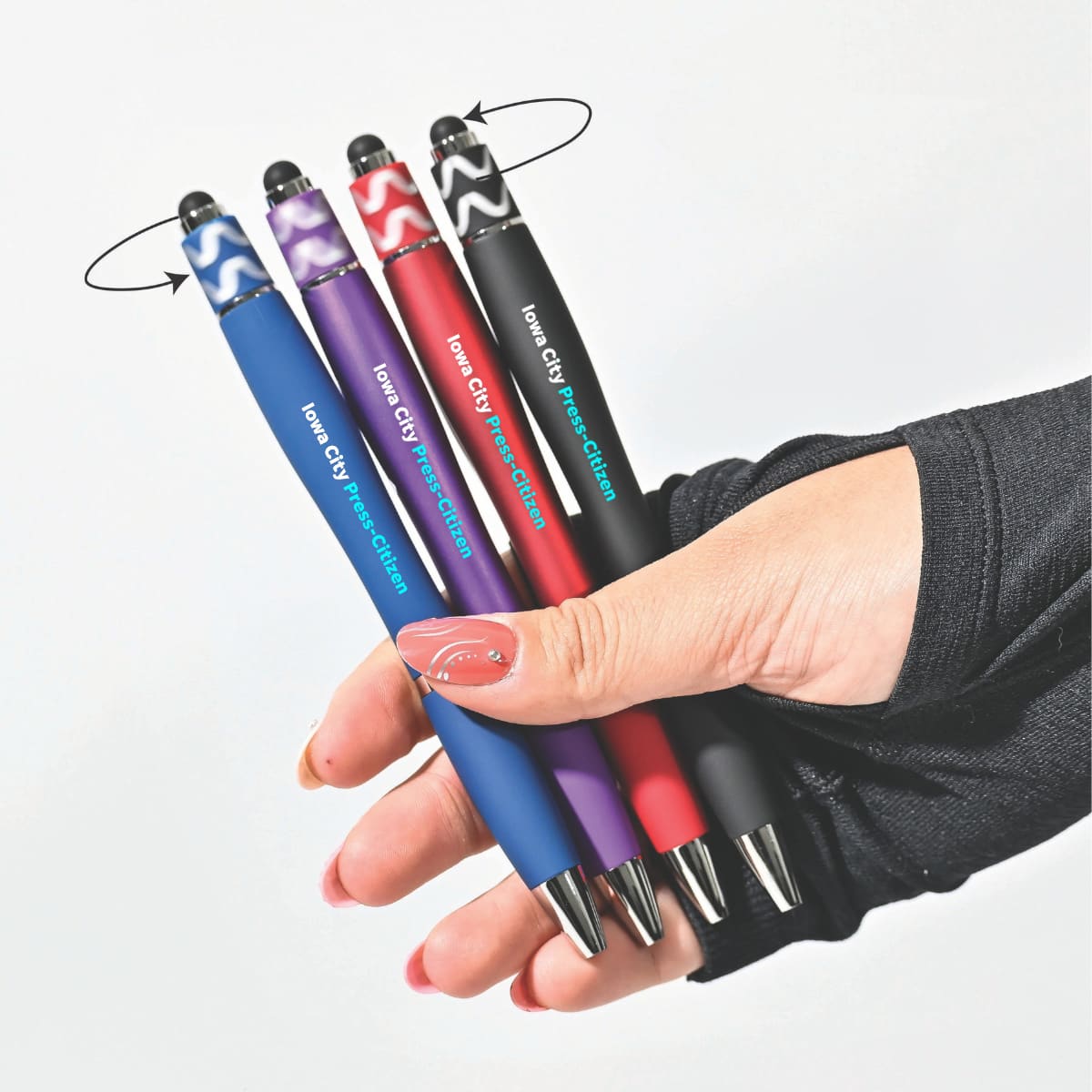 A hand holding four spinner fidget pens in blue, red, purple, and black, each with a stylus tip and unique designs. Spinner Fidget Pen - Image 1