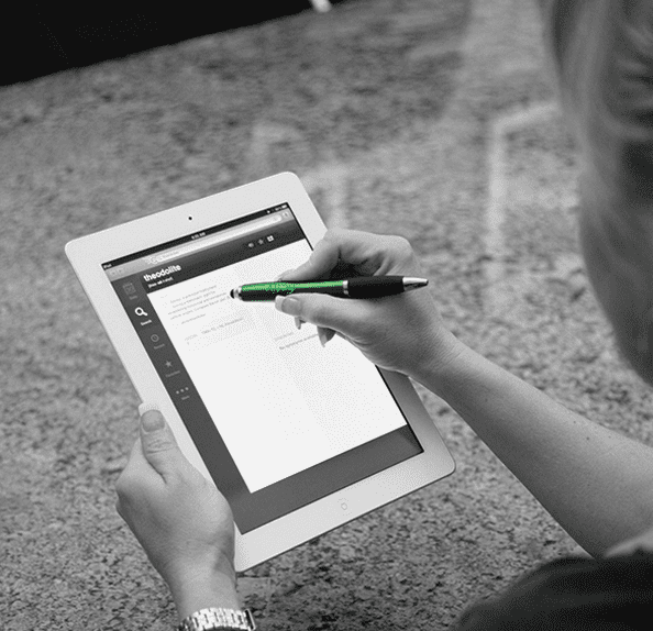 A person using a black stylus pen on a tablet, with a light-coloured background. The stylus has a sleek design and branding. Grenada Stylus Pen - Image 1
