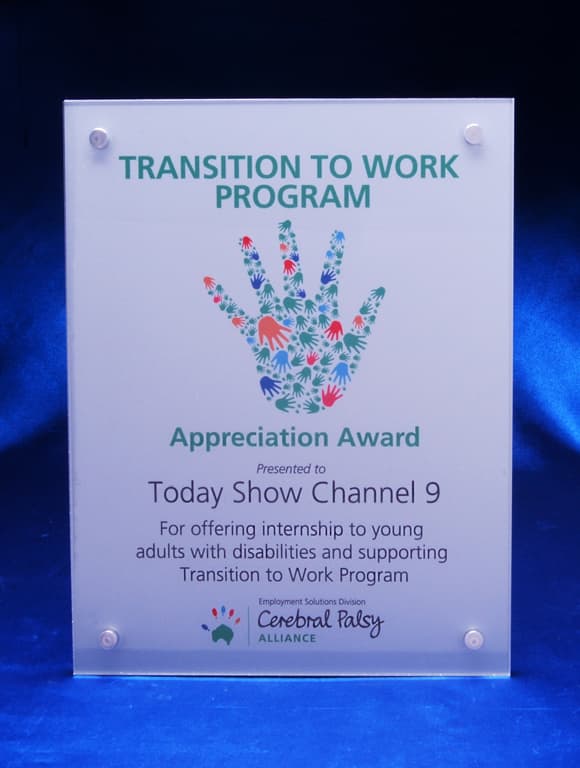 A clear acrylic award plaque with a floral handprint design and a blue satin background. It features a logo at the top. Full Face Acrylic Overlay on Satin Alloy Printed Plaque - Image 1