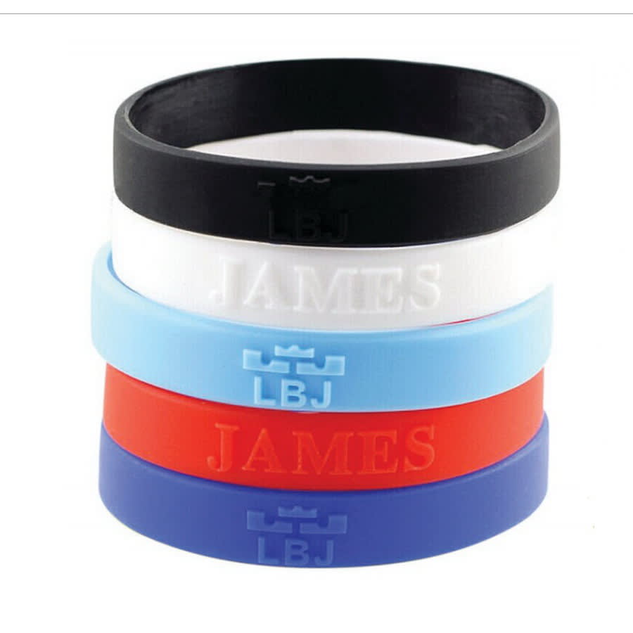 A stack of embossed silicone wristbands in black, white, light blue, red, and dark blue, featuring a logo. Embossed Wristband - Image 1