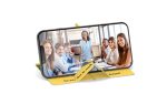 A yellow pop-up slider phone stand displays a smartphone featuring a group photo of smiling individuals in a meeting setting.