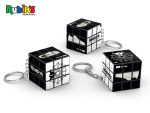 A Rubik's Cube 3x3 keychain in black and white, featuring three cubes on keyrings with a logo present.