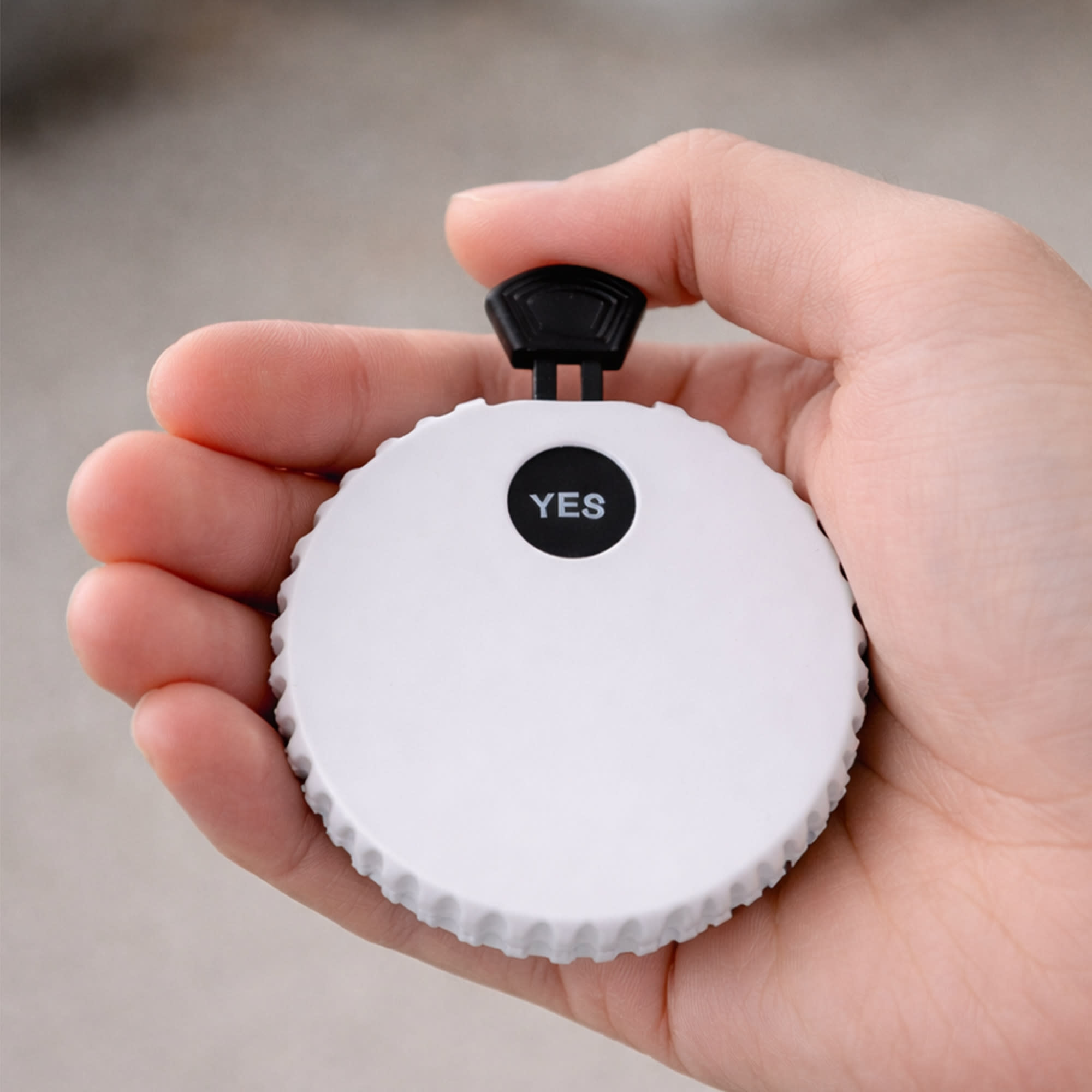 A drink bottle opener in white with a black toggle on top, held in a person's hand. Features a logo. Yes or No Game Set Bottle Opener - Image 1