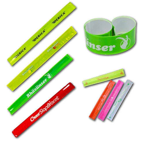 A variety of reflective snap wristbands in bright green, lime, red, and pink colours, featuring different logos and designs. Reflective Snap Wristband 230 x 30mm - Image 1