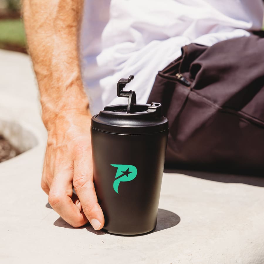 A travel cup in matte black with a green logo, featuring a secure lid and hand-held against a light background. Kona 350ml Travel Cup - Image 1