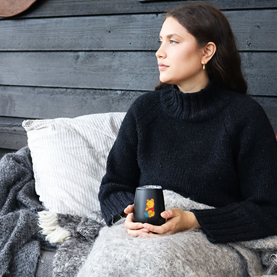 A drink mug with a Zen mirror finish in black, featuring a design, held by a person seated on a couch with cushions. Zen Mirror Finish Mugs (350mL) - Image 1