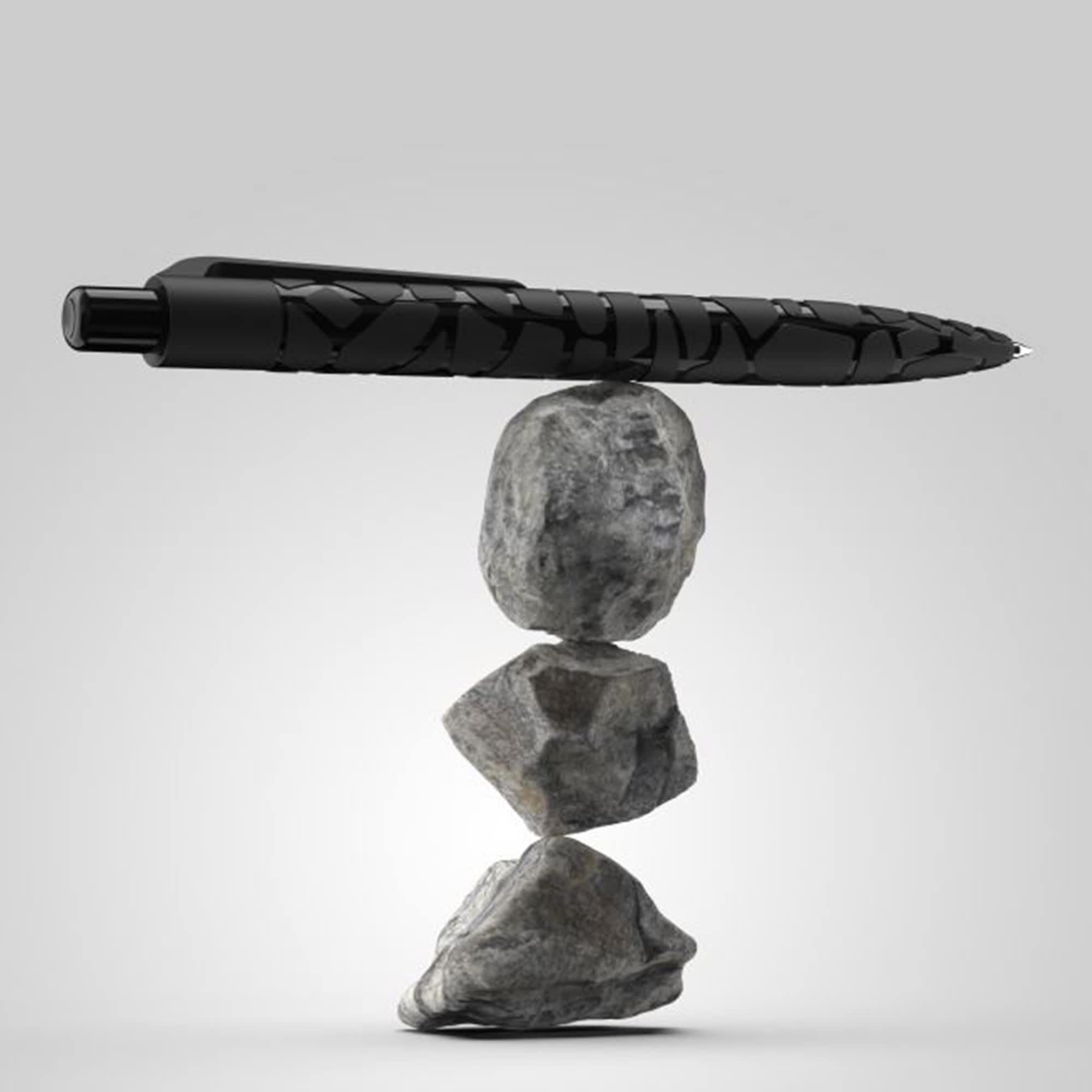 A black pen with a textured design balanced on three stacked rocks, showcasing the "Marko Stone Pen" product. Marko Stone Pen - Image 1