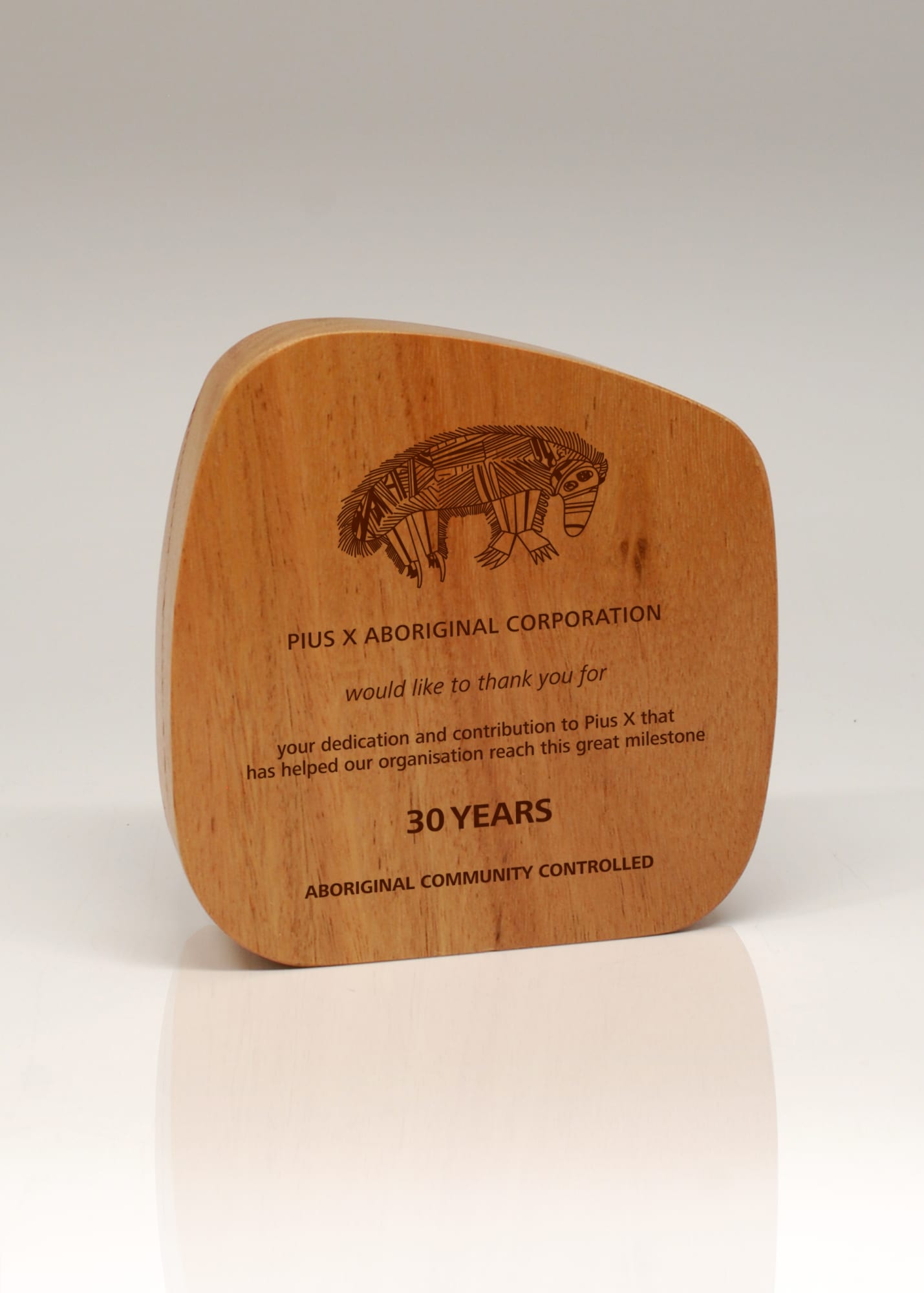 A wooden trophy with a curved shape, featuring an engraved design and text celebrating 30 years of achievement. Australian Select Grade Blackbutt Pebble Trophy - Image 1